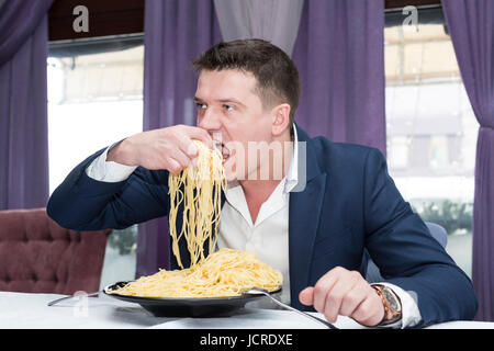 Homme mangeant une grande portion de pâtes dans un restaurant Banque D'Images