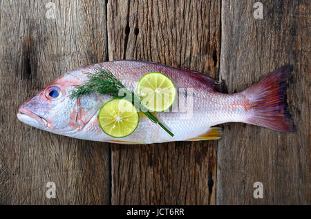 Le vivaneau rouge de poisson frais du marché de la pêche avec le citron situé sur la plaque en bois. Banque D'Images