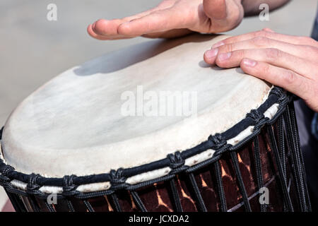 Musicien de rue jouant du tambour djembé africain à l'extérieur. Gros plan du mans mains. Banque D'Images