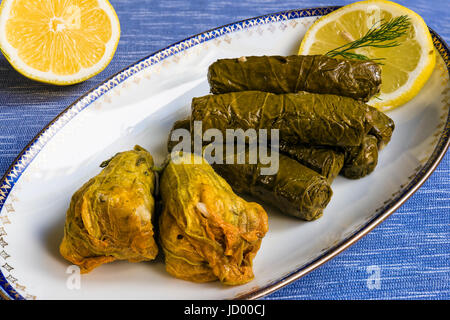 De délicieuses feuilles de vigne farcies et squash blossoms (le dolma traditionnels de la cuisine méditerranéenne) dans la plaque blanche avec tranche de citron et d'aneth Banque D'Images