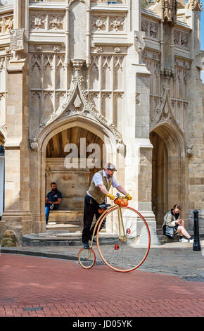 Homme barbu équitation réplique moderne Penny Farthing location par Chichester Croix, une croix sur le marché dans le centre de Chichester, une ville dans le West Sussex, UK Banque D'Images