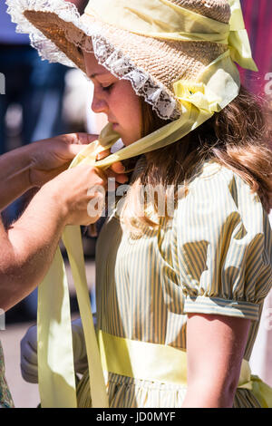 Portrait of teenage girl, habillés en costume victorien, vert et bonnet. Mains aidant à fixer le ruban sous sa chaîne pour fixer le chapeau. Une partie de l'Broadstairs Dickens Festival. Banque D'Images