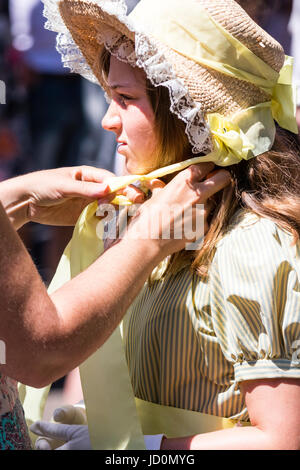 Portrait of teenage girl, habillés en costume victorien, vert et bonnet. Mains aidant à fixer le ruban sous sa chaîne pour fixer le chapeau. Une partie de l'Broadstairs Dickens Festival. Banque D'Images