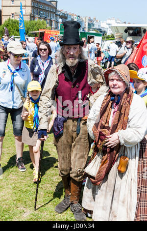 Charles Dickens event à Broadstairs, Angleterre. Couple, sale et délabré de la Marine "' et sa femme marcher vers l'observateur. À l'extérieur sur la pelouse avec beaucoup d'autres personnes autour. Banque D'Images