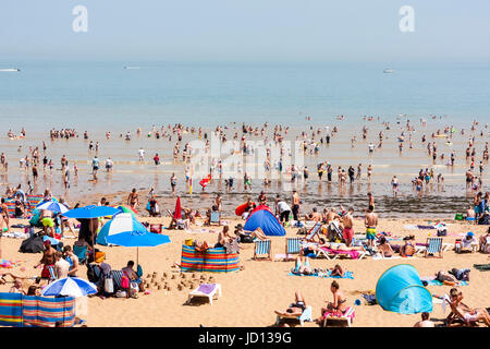 Les gens sur la plage pendant la saison chaude à Broadstairs station balnéaire. Soleil d'avant-plan les baigneurs sur le sable, et puis mer avec beaucoup de gens ramer. Banque D'Images