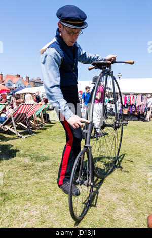 Homme debout tenant son Penny Farthing location début de l'époque victorienne sur l'herbe au cours de Broadstairs Dickens semaine. En uniforme et le chapeau. Low angle view point. Banque D'Images