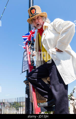 M. William Thompkins, Lamplighter, Charles Dickens caractère, histoire. Vêtu de blanc manteau et chapeau de paille, se dresse sur l'échelle contre la lumière avec Union Jack. Banque D'Images