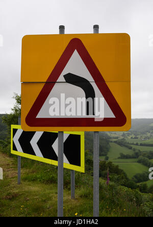 Signalisation routière sur virage dans la route, fond jaune avec triangle d'avertissement rouge et fond de campagne à powys, pays de galles royaume-uni Banque D'Images