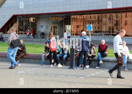 Les jeunes hommes non identifiés et les femmes (filles et garçons) fumer dehors dans une zone désignée pour les fumeurs près de la gare. Jour d'été ensoleillé. Banque D'Images