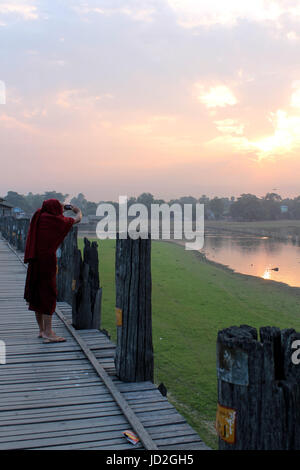 U-Bein Bridge/Amarapura - Myanmar 22 Janvier 2016 : le moine bouddhiste la capture de l'aube sur le lac Taungthaman avec son téléphone mobile. Banque D'Images