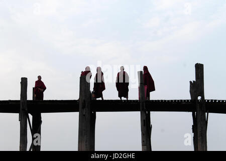U-Bein Bridge/Amarapura - Myanmar 22 Janvier 2016 : cinq moines bouddhistes sur leur promenade quotidienne à travers les mondes plus long pont pied juste avant le lever du soleil. Banque D'Images