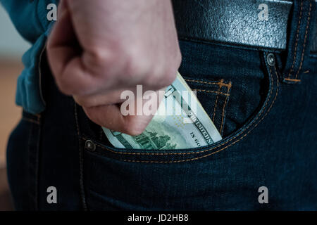 L'argent de papier homme accrochant fermement coincé dans sa main, essayant de se glisser dans votre poche Banque D'Images