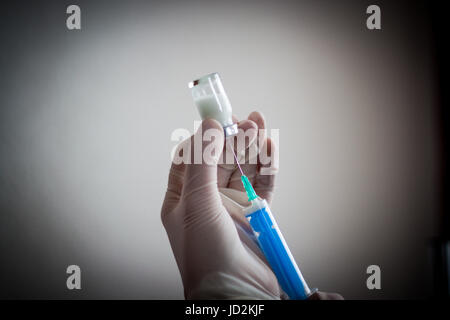 Jeune médecin prépare une injection à un patient, le liquide injecté dans l'aiguille, maintenant très attentivement Banque D'Images