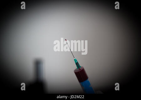 Doctor holding une aiguille dans sa main dans laquelle il a du sang sur l'extrémité de l'aiguille est situé à gouttes de sang Banque D'Images