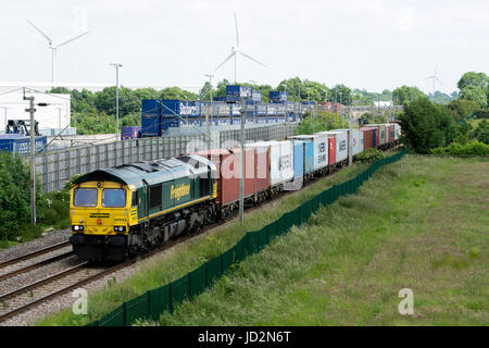 Locomotive diesel de la classe 66 tirant un freightliner train passé Tesco entrepôt, DIRFT, Northamptonshire, Angleterre Banque D'Images