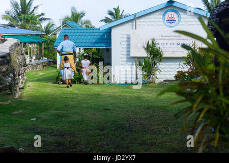 Dimanche matin, une île du Pacifique, le père de famille traditionnelle robe de Niue conduit ses deux filles à l'entrée de l'Église catholique Alofi, Banque D'Images