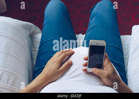 Pregnant woman holding smartphone dans ses mains, vue du dessus Banque D'Images
