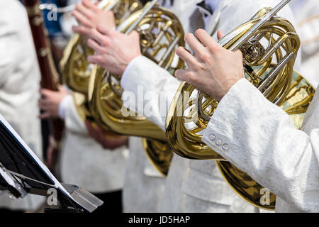 Au cours de la performance de l'orchestre de rue. des musiciens en costumes blancs jouant cors. Banque D'Images