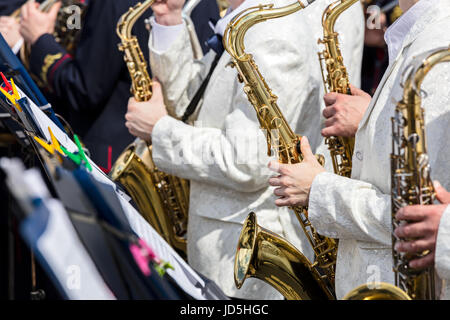 Saxophones dans les mains de musiciens de l'orchestre pendant les concerts de rue Banque D'Images