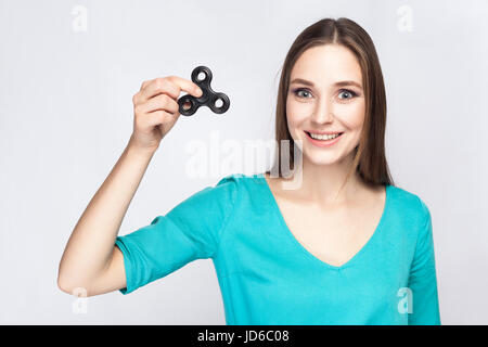 Belle jeune fille maintenant et jouer avec fidget spinner. studio shot sur fond blanc. Banque D'Images