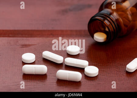 Les bouteilles de pilules brun et tas de pilules blanches sur la table en bois Banque D'Images