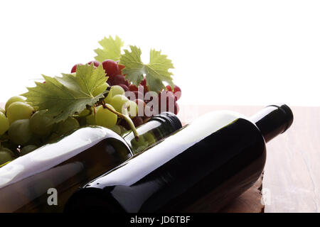 Bouteille de vin rouge et blanc, raisin et bouchons sur table en bois Banque D'Images
