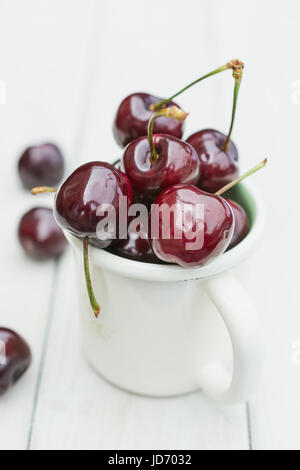 Mug rempli de cerises sur une table en bois Banque D'Images