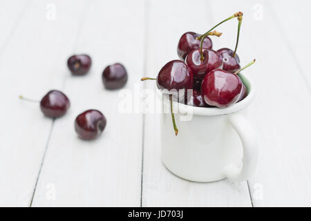 Mug rempli de cerises sur une table en bois Banque D'Images