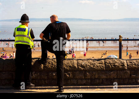 Barry, Royaume-Uni. 18 Juin, 2017. Deux agents de police de prendre un moment pour profiter du soleil comme les foules se rassemblent à la plage le 18 juin 2017. Comme les températures atteignent 28 degrés Celsius dans le sud du Pays de Galles des centaines d'amateurs de soleil se rassemblent à la plage pour profiter de l'été. Crédit : Jim Wood/Alamy Live News Banque D'Images