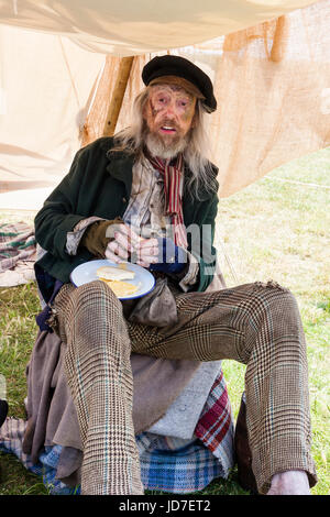 L'Angleterre, Broadstairs, Dickens Semaine. 'Ancien' Marine marin de la Royal Navy et survivant de la bataille de Trafalgar, manger un repas de pain et de fromage. Sale et portant des vêtements déchirés. Membre de la voix de Londres victorien Living History group. Banque D'Images