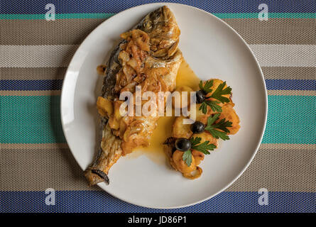 Le poisson cuit au four, accompagné de pommes de terre à l'or et les olives dans un plat blanc. Plat typiquement portugaise. Banque D'Images