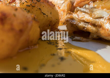 Le poisson cuit au four, accompagné de pommes de terre à l'or et les olives dans un plat blanc. Plat typiquement portugaise. Banque D'Images