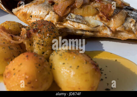Le poisson cuit au four, accompagné de pommes de terre à l'or et les olives dans un plat blanc. Plat typiquement portugaise. Banque D'Images