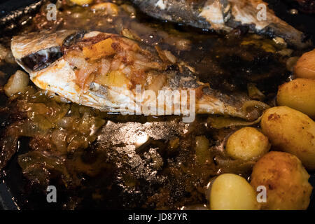 Le poisson cuit au four, accompagné de pommes de terre à l'or et les olives dans un plat blanc. Plat typiquement portugaise. Banque D'Images
