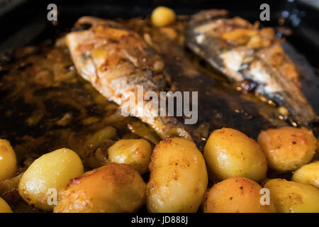 Le poisson cuit au four, accompagné de pommes de terre à l'or et les olives dans un plat blanc. Plat typiquement portugaise. Banque D'Images