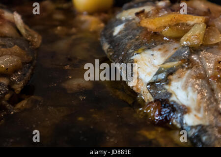 Le poisson cuit au four, accompagné de pommes de terre à l'or et les olives dans un plat blanc. Plat typiquement portugaise. Banque D'Images