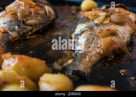 Le poisson cuit au four, accompagné de pommes de terre à l'or et les olives dans un plat blanc. Plat typiquement portugaise. Banque D'Images