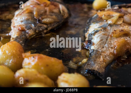 Le poisson cuit au four, accompagné de pommes de terre à l'or et les olives dans un plat blanc. Plat typiquement portugaise. Banque D'Images