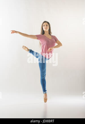 Femme ballerine sur une jambe, le port d'habits, studio shot. caucasian monter assez maigre athletic Banque D'Images