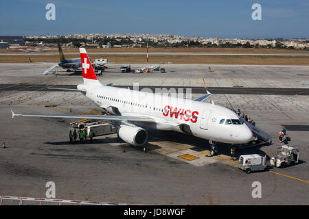 Le transport aérien commercial en Europe. Les passagers d'une Swiss International Air Lines Airbus A320 jet plane sur le tarmac à l'Aéroport International de Malte Banque D'Images