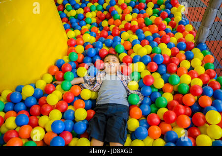 Un jeune garçon couché dans une piscine à balles. Banque D'Images