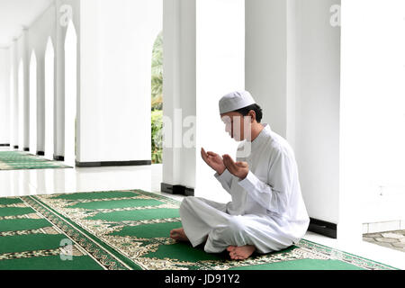 Portrait of Asian Muslim man raising hand et prier dans la mosquée Banque D'Images