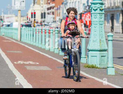 Randonnée à vélo avec un enfant. Femme à vélo sur une piste cyclable, portant un enfant. Banque D'Images