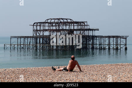 Un homme aime le temps chaud sur la plage de Brighton, East Sussex. Banque D'Images