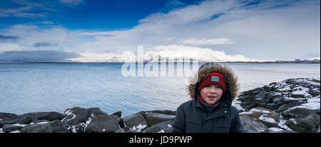 Portrait de jeune garçon avec derrière la mer et ciel bleu, de l'Islande, de l'Europe. Nature de l'Islande 2017 hiver froid Banque D'Images