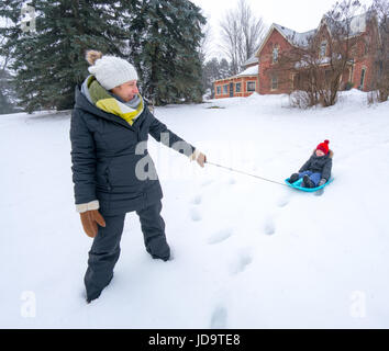 À l'extérieur à jour, mère fils tirant sur un traîneau dans la neige, l'Ontario, Canada. ontario canada hiver froid neige 2017 Banque D'Images