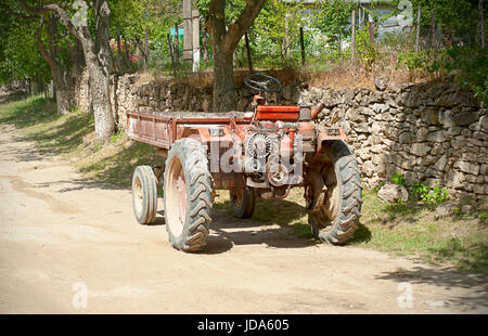 Vieux tracteur rouge parking sur la route dans le village Banque D'Images