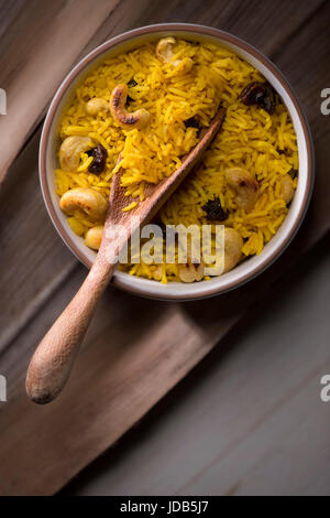 Le curcuma curcuma riz fait avec sol, le riz basmati, les raisins secs et les noix de cajou, sur un fond brun clair. Vue de dessus, soft focus. Banque D'Images