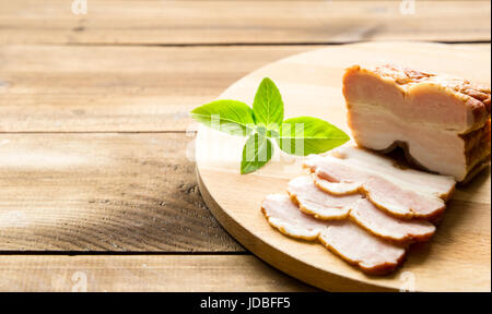 Les tranches de bacon fumé brut sur planche de bois que les herbes Banque D'Images