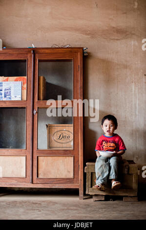 PAKSE, Laos, le 14 août : un petit garçon assis Laos manger dans la chambre de Pakse, Laos le 14 août 2010 Banque D'Images